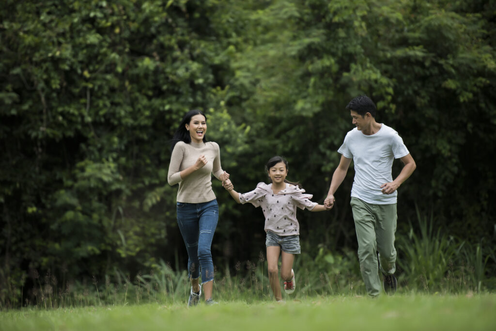 Happy family is having fun Mother, father and daughter are running in park.