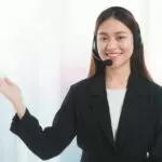 Portrait of Asian beautiful smiling woman customer support phone operator on window with city building background and copy space.Concept call center job service.