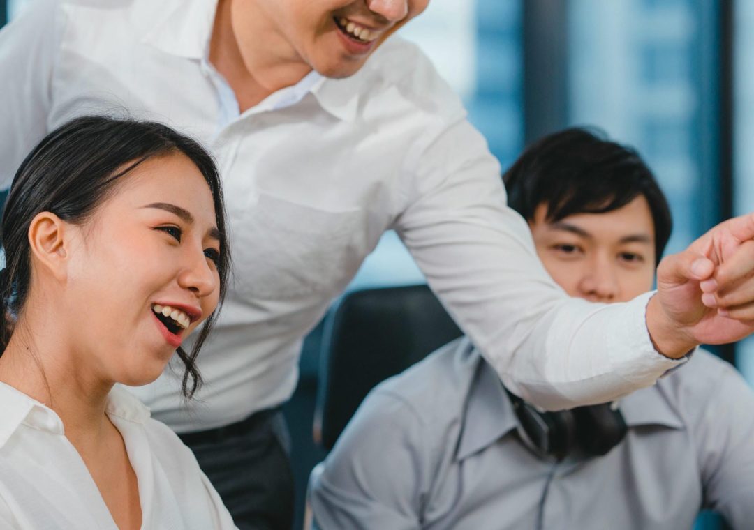Millennial group of young businesspeople Asia businessman and businesswoman celebrate giving five after dealing feeling happy and signing contract or agreement at meeting room in small modern office.